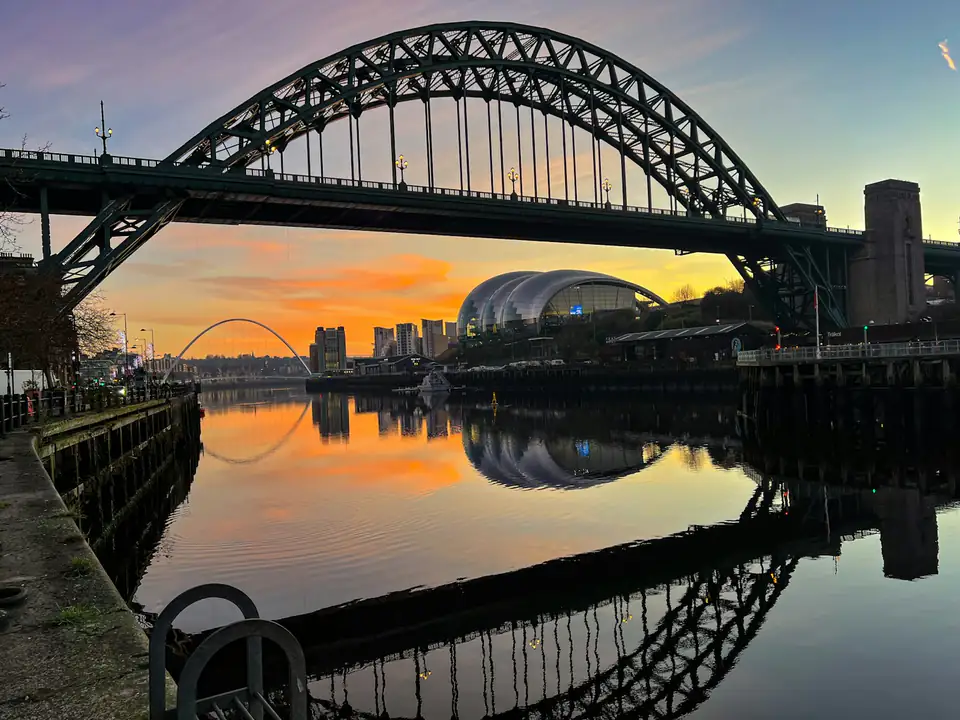 The Tyne Bridge and Sage Gateshead at sunset, seen across the river from the Gateshead Quays